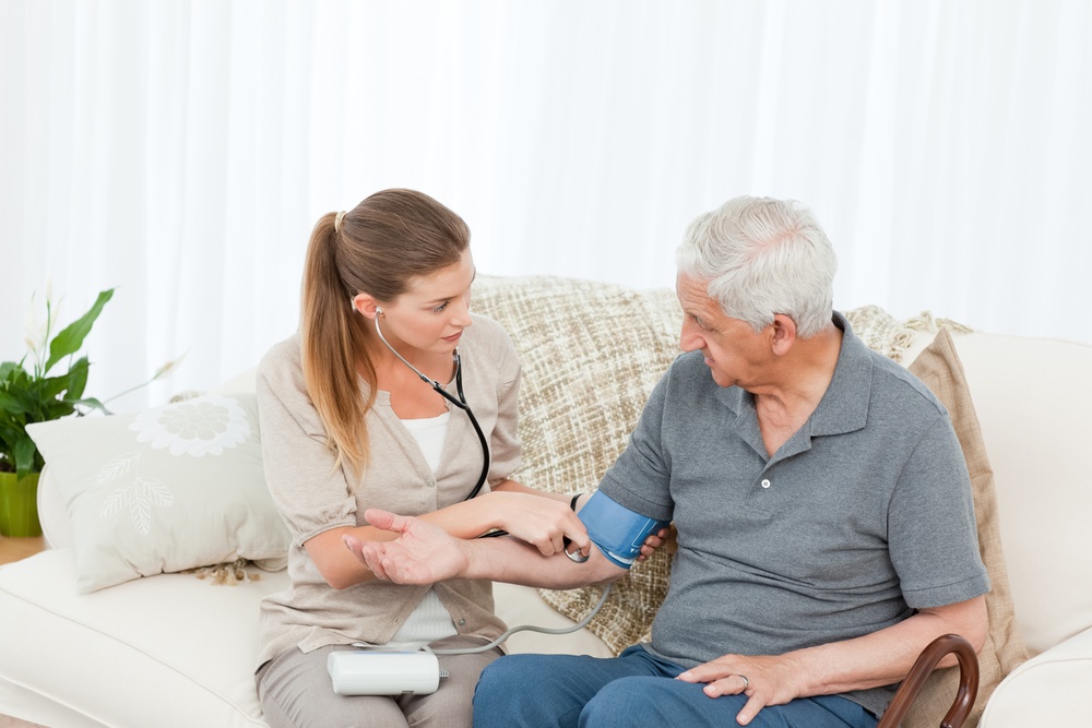 Lovely nurse helping her patient to do exercises at home